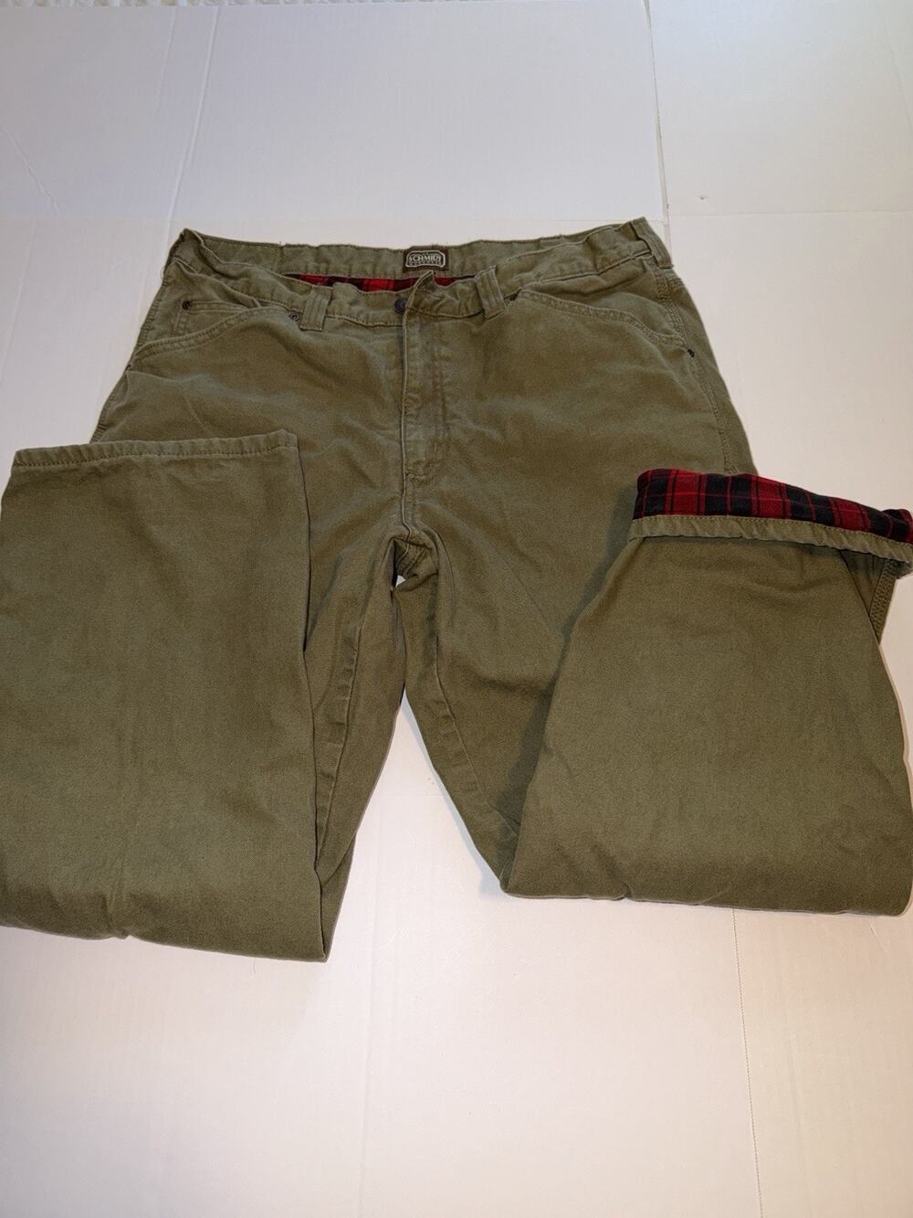 Schmidt Workwear men's olive green pants featuring a red flannel lining.